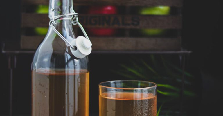 Cider - A Glass Bottle with Brown Liquid Beside a Glass of Cold Drink