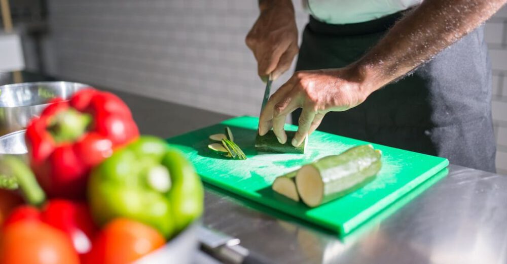 Recipes - A Person Slicing a Cucumber