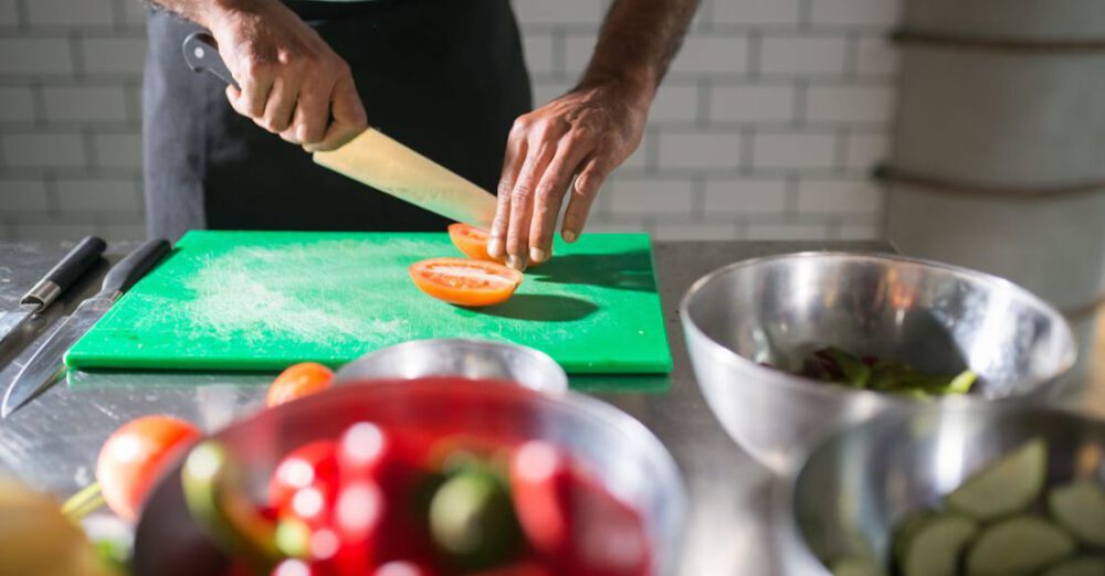 Recipes - A Person Slicing a Tomato